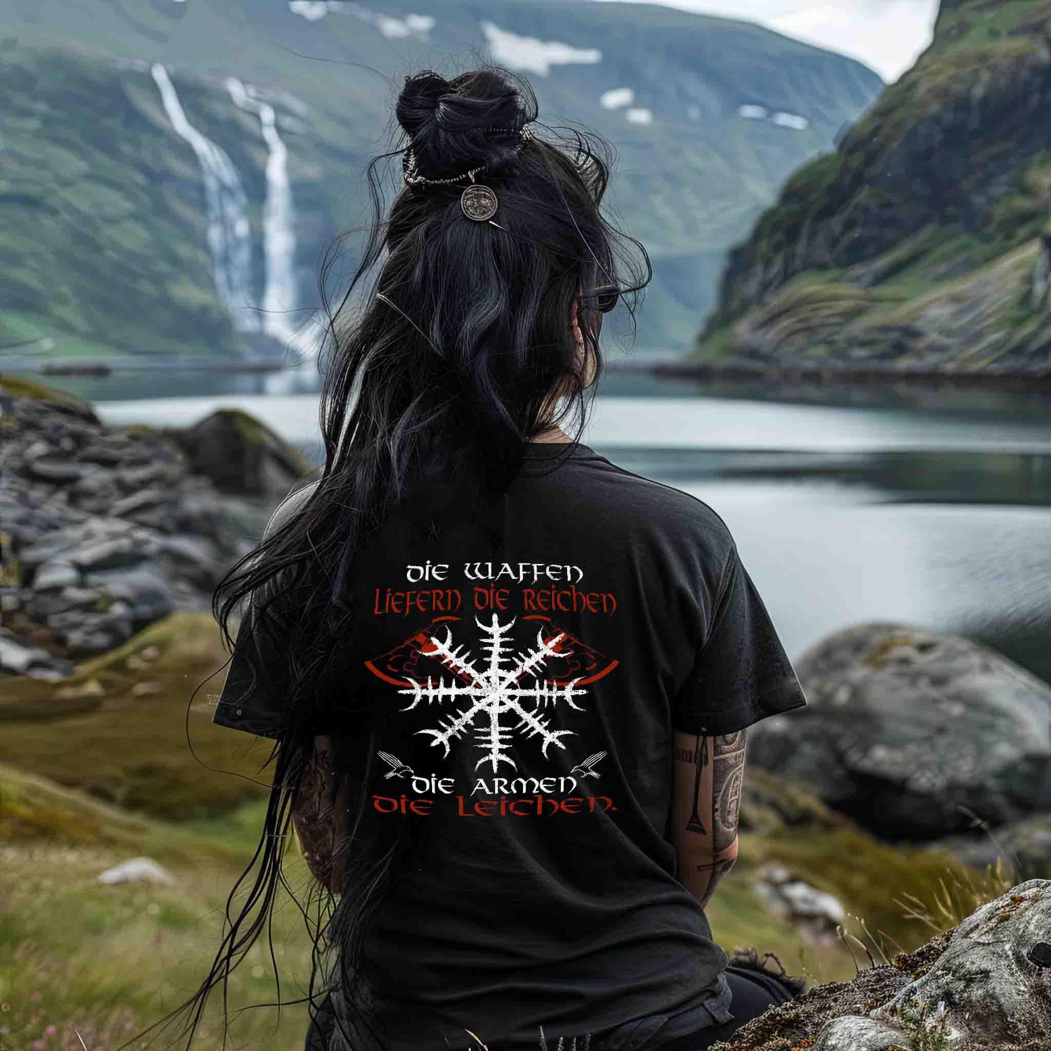 Frau mit Wikinger-Shirt und Runenmotiv sitzt am norwegischen Fjord, nordische Naturkulisse