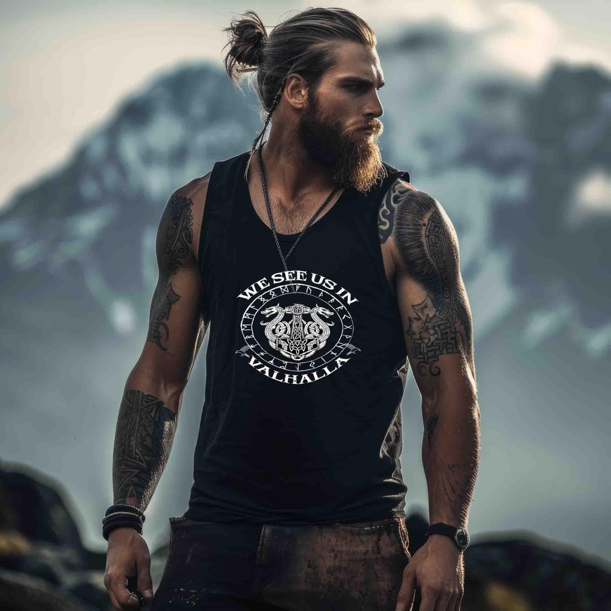 Viking mit Bart und tätowierten Armen in schwarzem Tanktop vor Bergen, nordische Streetwear