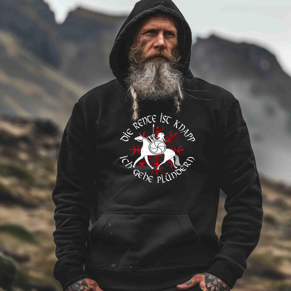 Älterer Mann im Wikinger-Hoodie mit Aufdruck 'Die Rente ist knapp, ich gehe plündern' vor nordischer Landschaft