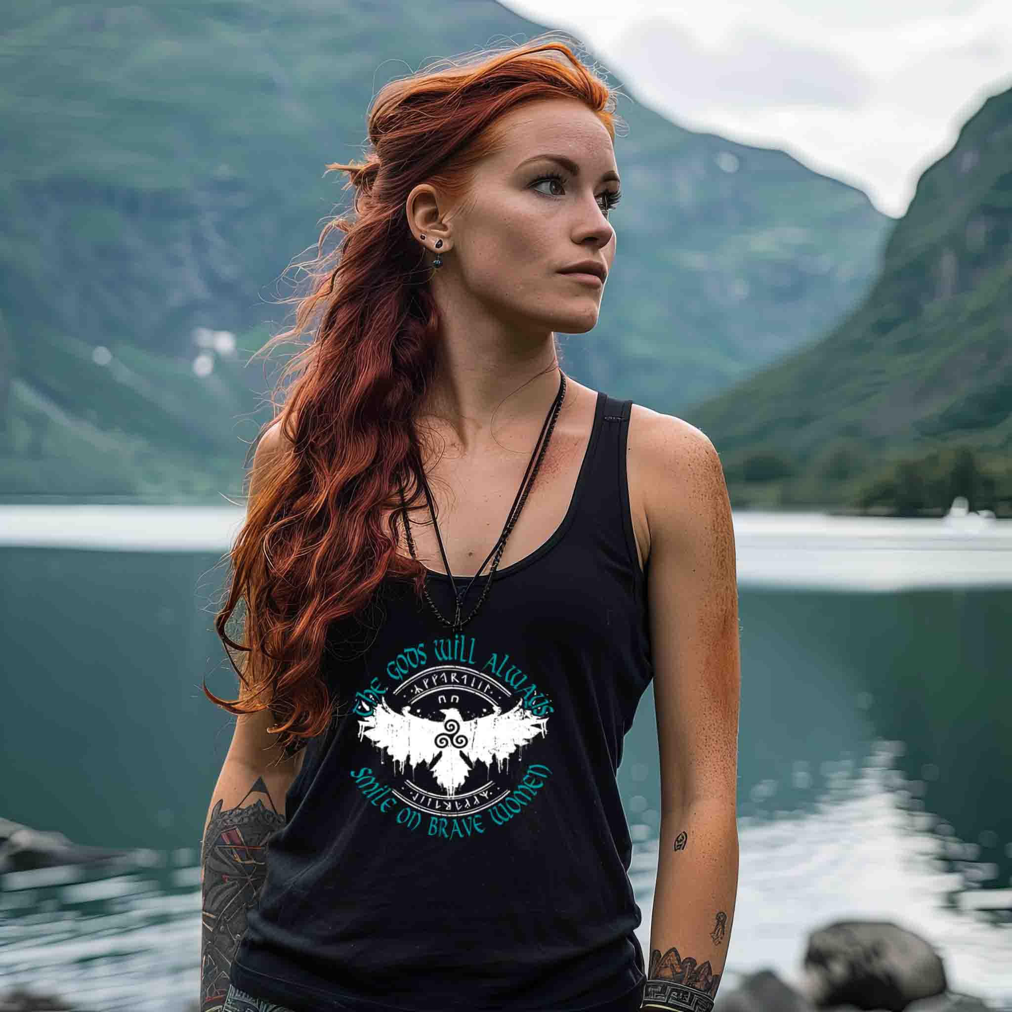 Woman wearing Schildmaiden Tanktop with the text "The Gods Will Always Smile on Brave Women," featuring a Celtic Triskelion and stylized eagle design.